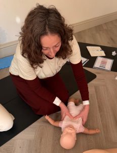 Baby first aid training session showing infant CPR chest compressions on a baby manikin
