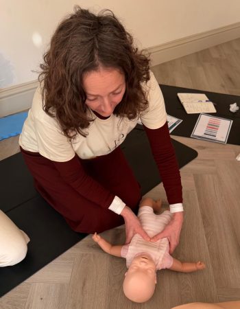 Baby first aid training session showing infant CPR chest compressions on a baby manikin