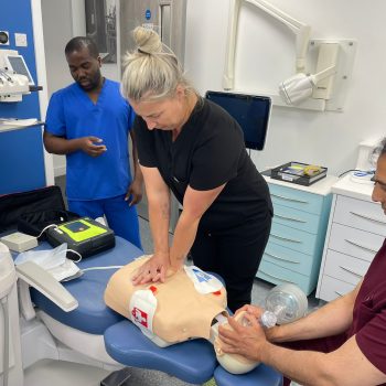 ILS training session showing healthcare professionals performing CPR and airway management with AED in a clinical setting